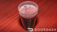 a glass filled with a purple drink on a wooden table